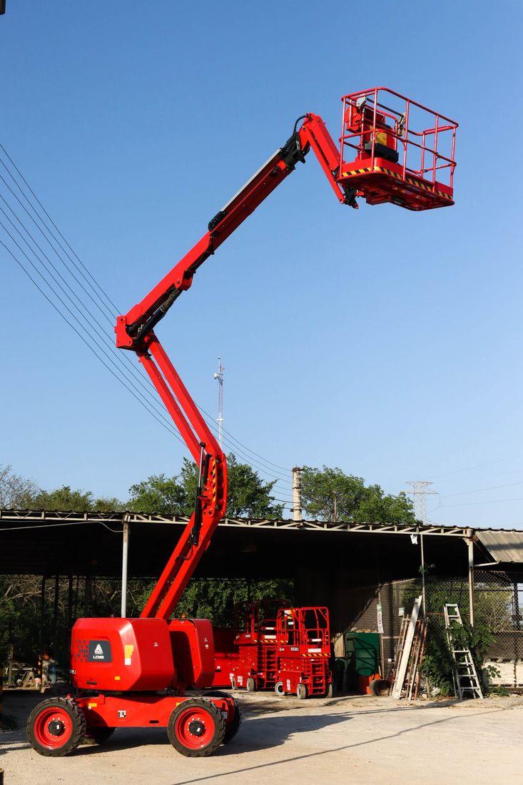 Plataforma articulada LGMG extendida, con plataformas de tijera al fondo del patio