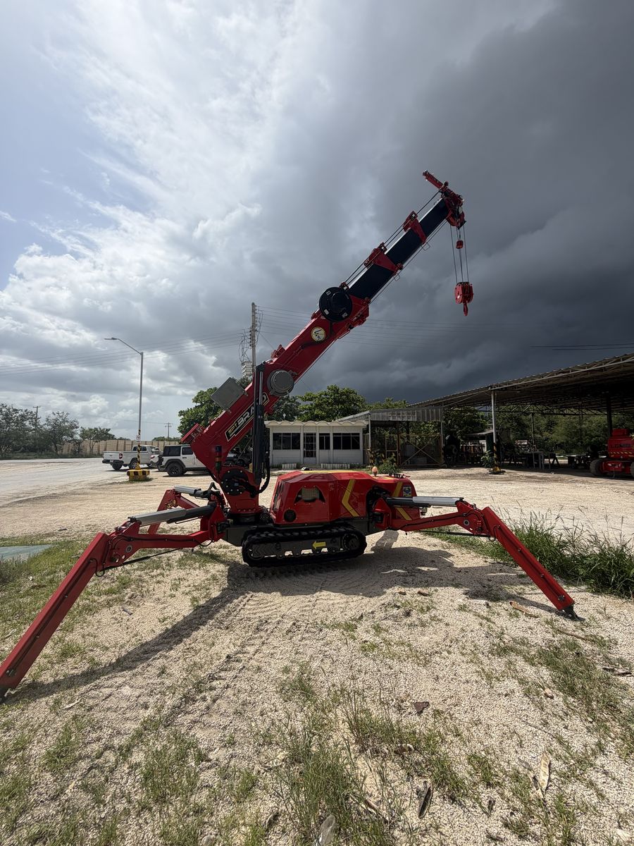 Grúa araña con la pluma extendida bajo un cielo de tormenta en el patio de SIMA